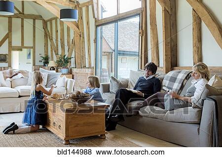 Stock Photo - Caucasian family relaxing in living room. Fotosearch