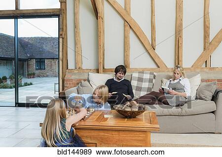 Stock Photo - Caucasian family relaxing in living room. Fotosearch