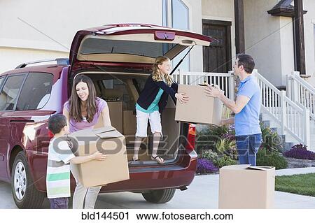 Stock Image - Caucasian family unpacking cardboard boxes from car. Fotosearch