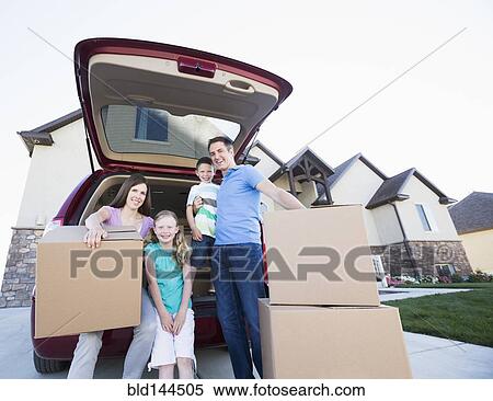 Stock Photography - Caucasian family unpacking cardboard boxes from car. Fotosearch