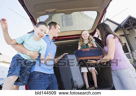 Stock Photo - Caucasian family unpacking suitcases from car. Fotosearch
