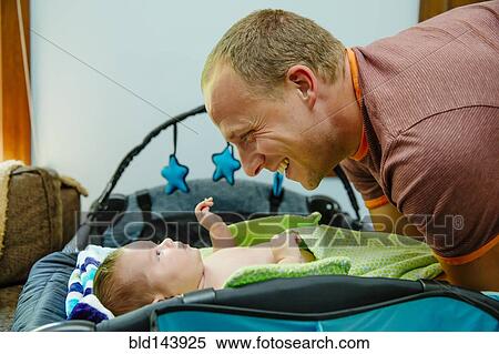 Stock Photography - Caucasian father admiring baby boy on crib. Fotosearch