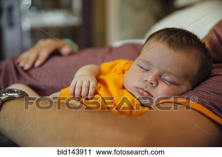 Stock Image - Caucasian father and baby boy sleeping on bed. Fotosearch