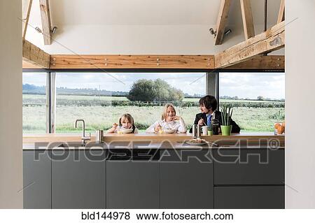 Stock Photo - Caucasian father and children eating breakfast in kitchen. Fotosearch