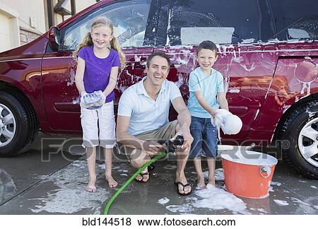 Caucasian father and children washing car in driveway View Large Photo Image Stock Photo - Caucasian father and children washing car in driveway. Fotosearch