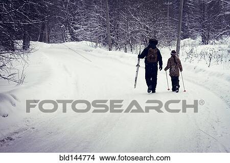 Picture - Caucasian father and daughter cross-country skiing on snowy road. Fotosearch