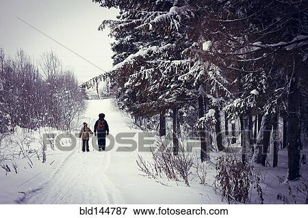 Stock Photo - Caucasian father and daughter cross-country skiing on snowy road. Fotosearch