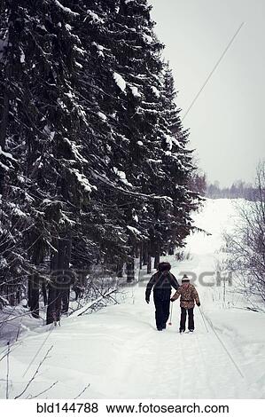 Stock Photo - Caucasian father and daughter cross-country skiing on snowy road. Fotosearch