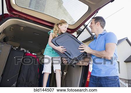 Stock Photo - Caucasian father and daughter unpacking suitcases from car. Fotosearch