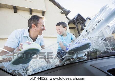 Stock Image - Caucasian father and son washing car windshield. Fotosearch