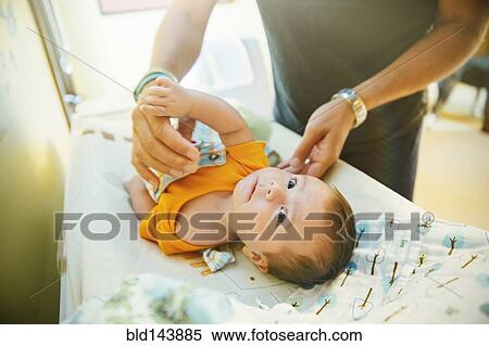 Stock Photography - Caucasian father changing diaper of baby boy. Fotosearch