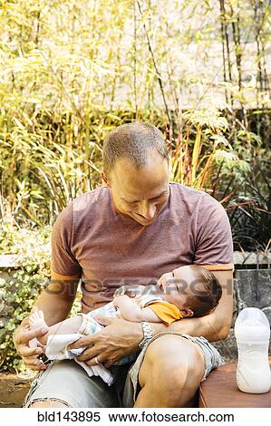 Caucasian father feeding baby boy in backyard View Large Photo Image Stock Photography - Caucasian father feeding baby boy in backyard. Fotosearch