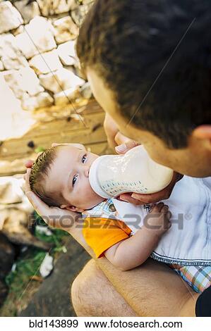 Caucasian father feeding baby boy outdoors View Large Photo Image Stock Photo - Caucasian father feeding baby boy outdoors. Fotosearch