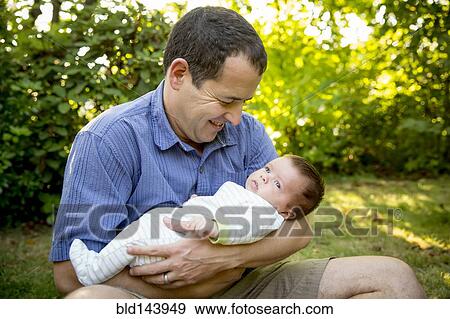 Caucasian father holding baby boy in backyard View Large Photo Image Stock Photo - Caucasian father holding baby boy in backyard. Fotosearch