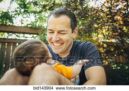 Picture - Caucasian father holding baby boy outdoors. Fotosearch