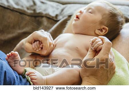 Caucasian father holding sleeping baby boy on sofa View Large Photo Image Stock Photo - Caucasian father holding sleeping baby boy on sofa. Fotosearch