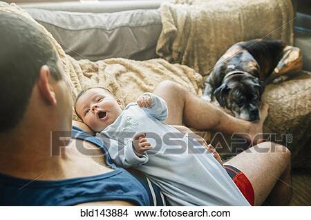 Caucasian father holding yawning baby boy in living room View Large Photo Image Picture - Caucasian father holding yawning baby boy in living room. Fotosearch