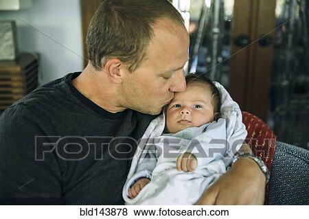 Stock Photo - Caucasian father kissing baby boy in living room. Fotosearch