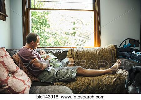 Caucasian father sitting with baby boy on sofa View Large Photo Image Stock Photo - Caucasian father sitting with baby boy on sofa. Fotosearch