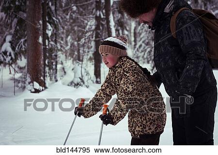 Stock Photography - Caucasian father teaching daughter to cross-country ski in forest. Fotosearch