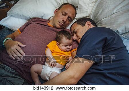 Stock Image - Caucasian fathers and baby boy sleeping on bed. Fotosearch