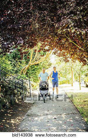 Caucasian gay couple jogging with stroller on sidewalk View Large Photo Image Stock Photo - Caucasian gay couple jogging with stroller on sidewalk. Fotosearch