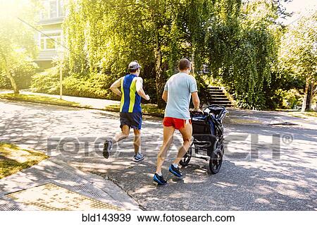 Caucasian gay couple jogging with stroller in neighborhood View Large Photo Image Stock Photo - Caucasian gay couple jogging with stroller in neighborhood. Fotosearch