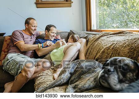 Caucasian gay couple playing with baby boy on sofa View Large Photo Image Stock Image - Caucasian gay couple playing with baby boy on sofa. Fotosearch