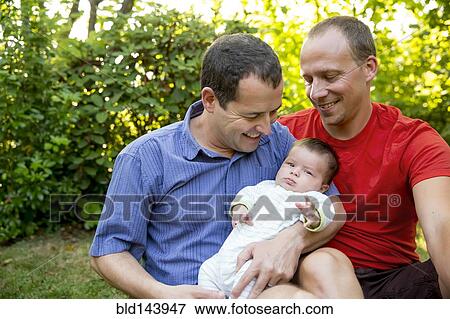 Caucasian gay couple smiling with baby boy in backyard View Large Photo Image Stock Photo - Caucasian gay couple smiling with baby boy in backyard. Fotosearch