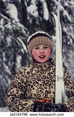 Stock Photo - Caucasian girl carrying skis in forest. Fotosearch