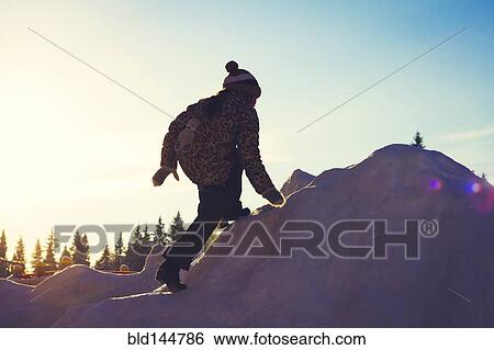 Stock Photograph - Caucasian girl climbing snowy hill. Fotosearch