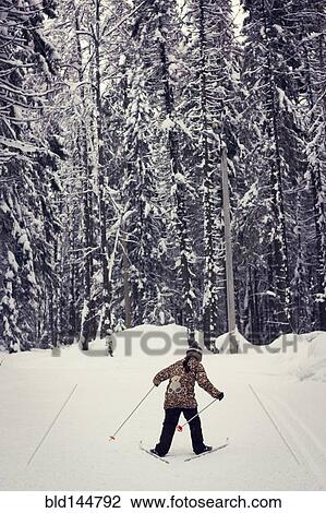 Stock Image - Caucasian girl cross-country skiing in forest. Fotosearch