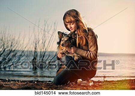 Caucasian girl petting dog near remote lake View Large Photo Image Picture - Caucasian girl petting dog near remote lake. Fotosearch