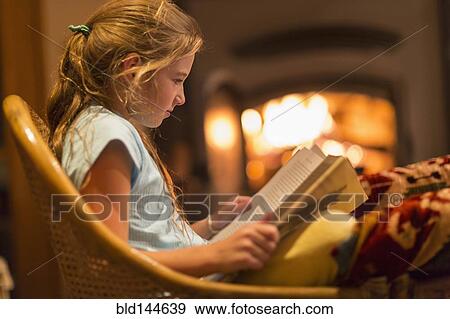 Stock Photo - Caucasian girl reading in living room. Fotosearch