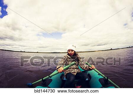 Stock Image - Caucasian girl rowing canoe on lake. Fotosearch