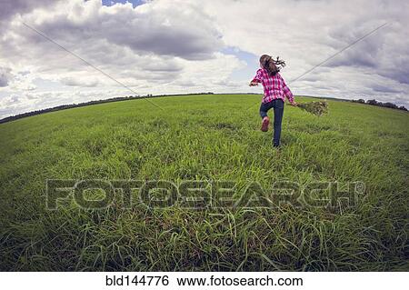 Stock Photograph - Caucasian girl running in grassy field. Fotosearch