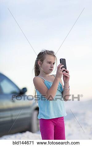 Caucasian girl taking cell phone photograph near car View Large Photo Image Stock Image - Caucasian girl taking cell phone photograph near car. Fotosearch