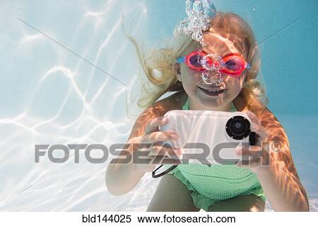 Stock Photography - Caucasian girl taking photograph underwater in pool. Fotosearch