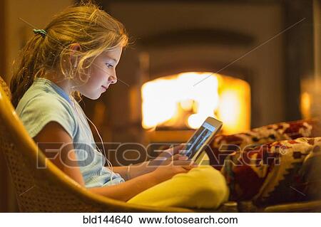 Caucasian girl using digital tablet in living room View Large Photo Image Stock Image - Caucasian girl using digital tablet in living room. Fotosearch