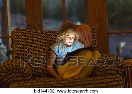 Caucasian girl using digital tablet in armchair at night View Large Photo Image Stock Image - Caucasian girl using digital tablet in armchair at night. Fotosearch
