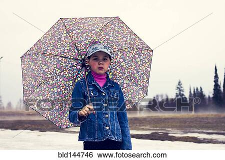 Stock Photograph - Caucasian girl walking under umbrella in snowy field. Fotosearch