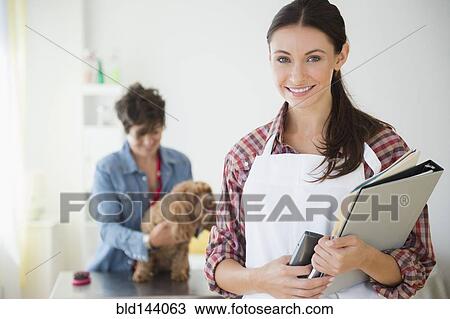 Stock Image - Caucasian groomer smiling in salon. Fotosearch