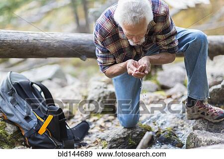 Caucasian hiker drinking water from creek in forest View Large Photo Image Stock Photo - Caucasian hiker drinking water from creek in forest. Fotosearch