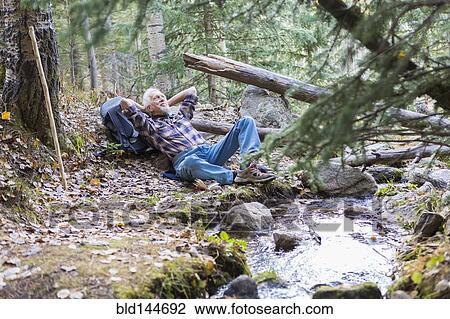 Stock Image - Caucasian hiker resting in forest. Fotosearch