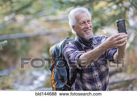 Caucasian hiker taking cell phone photograph in forest View Large Photo Image Stock Photo - Caucasian hiker taking cell phone photograph in forest. Fotosearch