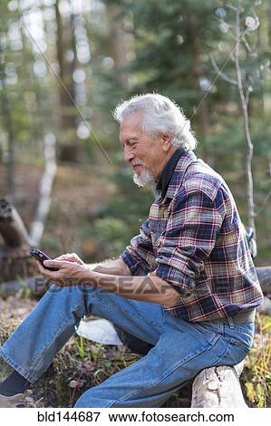 Stock Photo - Caucasian hiker using cell phone in forest. Fotosearch
