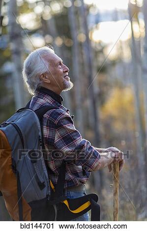 Stock Image - Caucasian hiker walking on dirt path in forest. Fotosearch