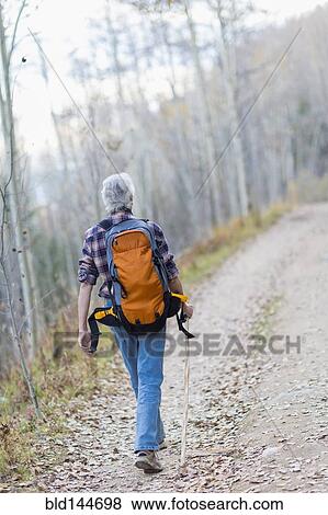 Stock Photo - Caucasian hiker walking on dirt path in forest. Fotosearch