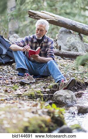 Stock Image - Caucasian hiker writing in forest. Fotosearch