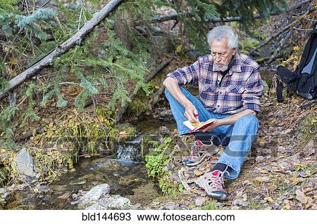 Stock Image - Caucasian hiker writing in forest. Fotosearch